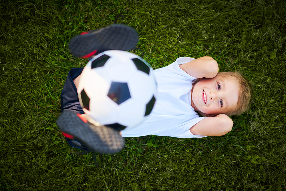 Little Boy practising soccer outdoors